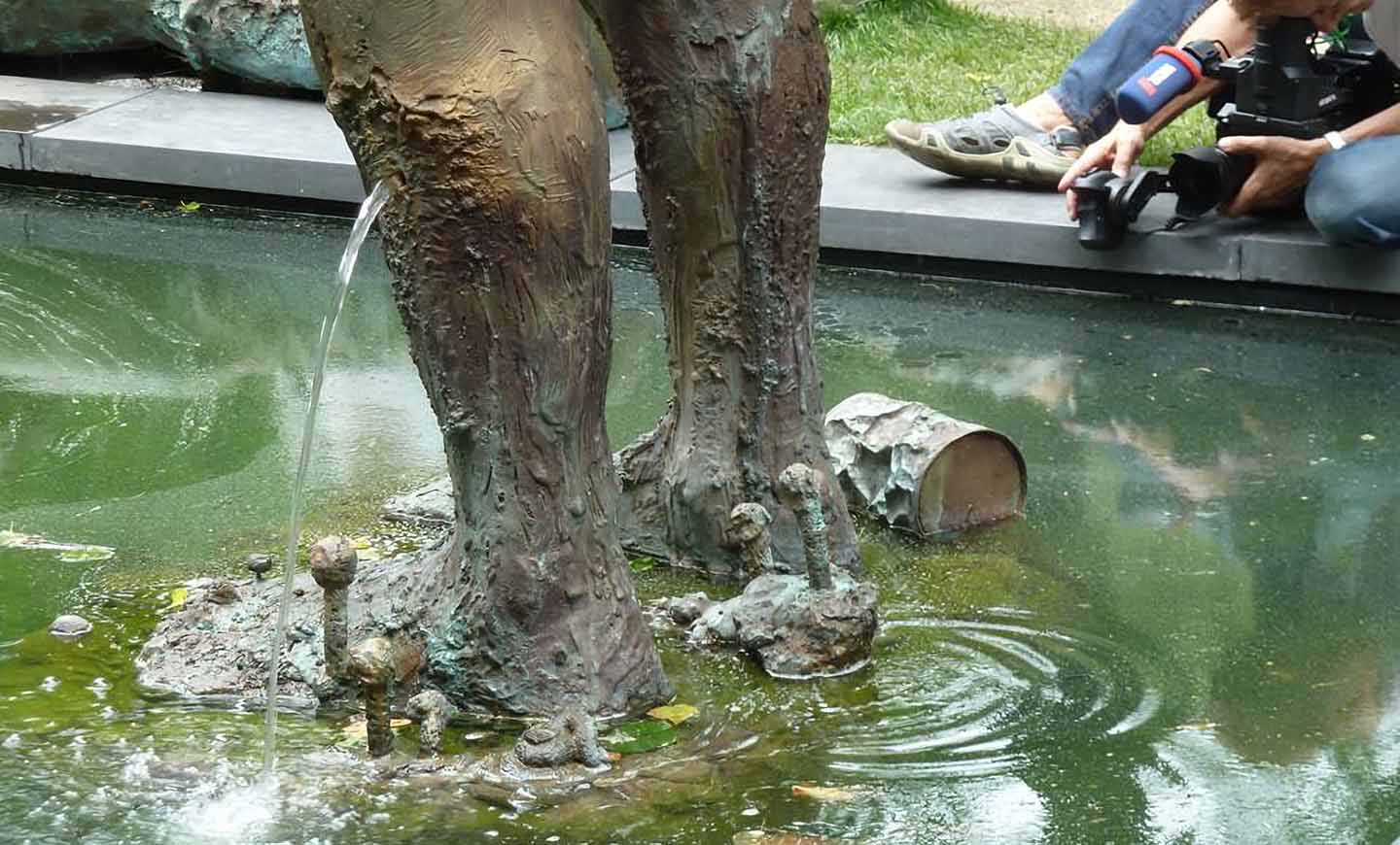The artist plays with the tradition of fountains: She does not let the water flow out of the classical ‚openings‘ of the figures.